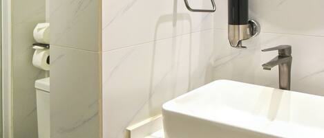 A bathroom with a white sink, a mirror, and a toilet.
