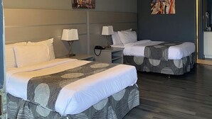 A hotel room with two beds, a nightstand, a lamp, a painting, and a ceiling light. - Hotel 10 Extended Stay (New Orleans)