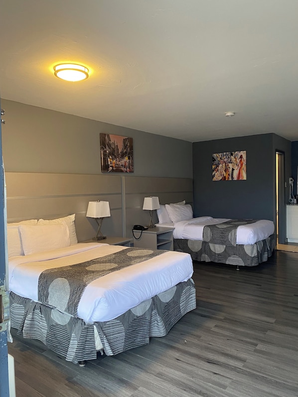 Habitación de hotel con dos camas, una mesita de noche, una lámpara, un cuadro y una luz en el techo.