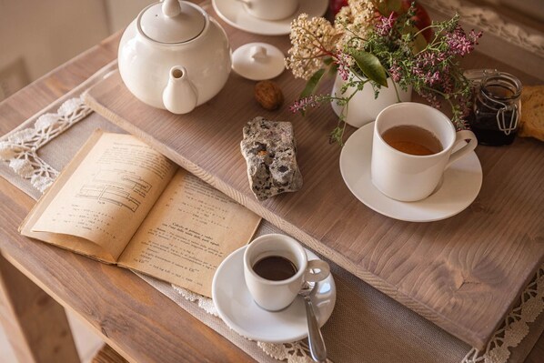 Una mesa de madera con una tetera, tazas, un libro, una roca y un jarrón con flores.