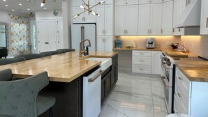 Een moderne keuken met witte kasten, een houten eiland en een hanglamp.