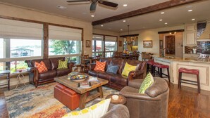 A spacious living room with leather sofas, a coffee table, and a dining area with a kitchen in the background.