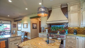 A spacious kitchen with granite countertops, a large island, stainless steel appliances, and wooden cabinetry.