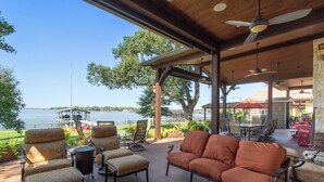An outdoor patio with seating, a view of the water, and a covered area with a ceiling fan.