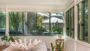 A room with a large window, a marble table, and potted plants.