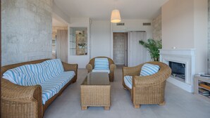 A living room with wicker furniture, a fireplace, and a stone wall. - Petrina 4 villa,next to beach & taverns,South Crete (Keratokambos)