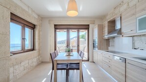 A modern kitchen with a dining area, large windows, and a view of the sea. - Petrina 4 villa,next to beach & taverns,South Crete (Keratokambos)