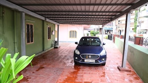 A covered car parking area with a blue car parked in the center. - Sri sapthagiri lodge (Chirala)
