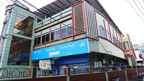 A multi-story building with a blue sign for Canara Bank and another sign in a local language.