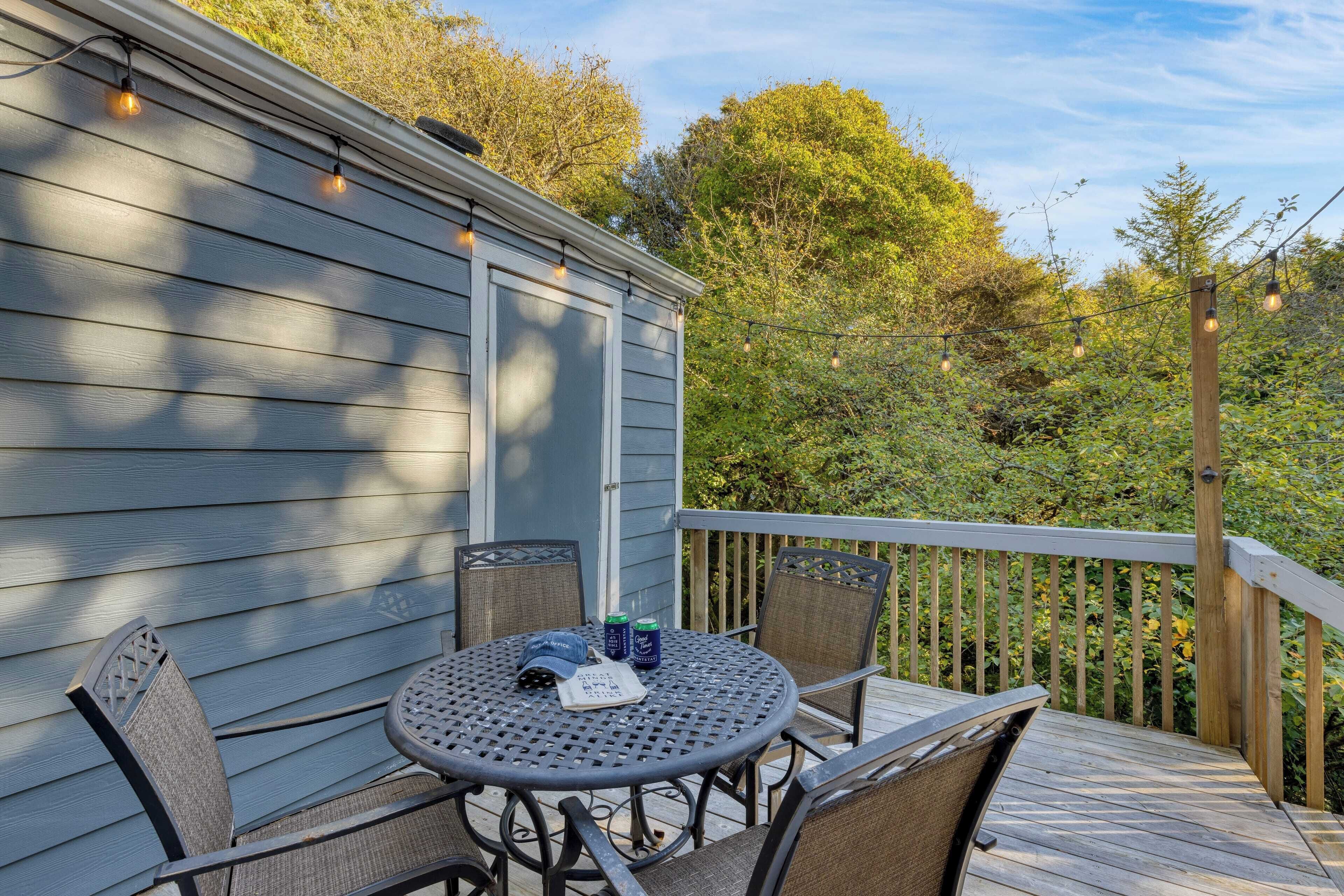 A wooden deck with a round table and chairs, a small shed, and a wooden railing.
