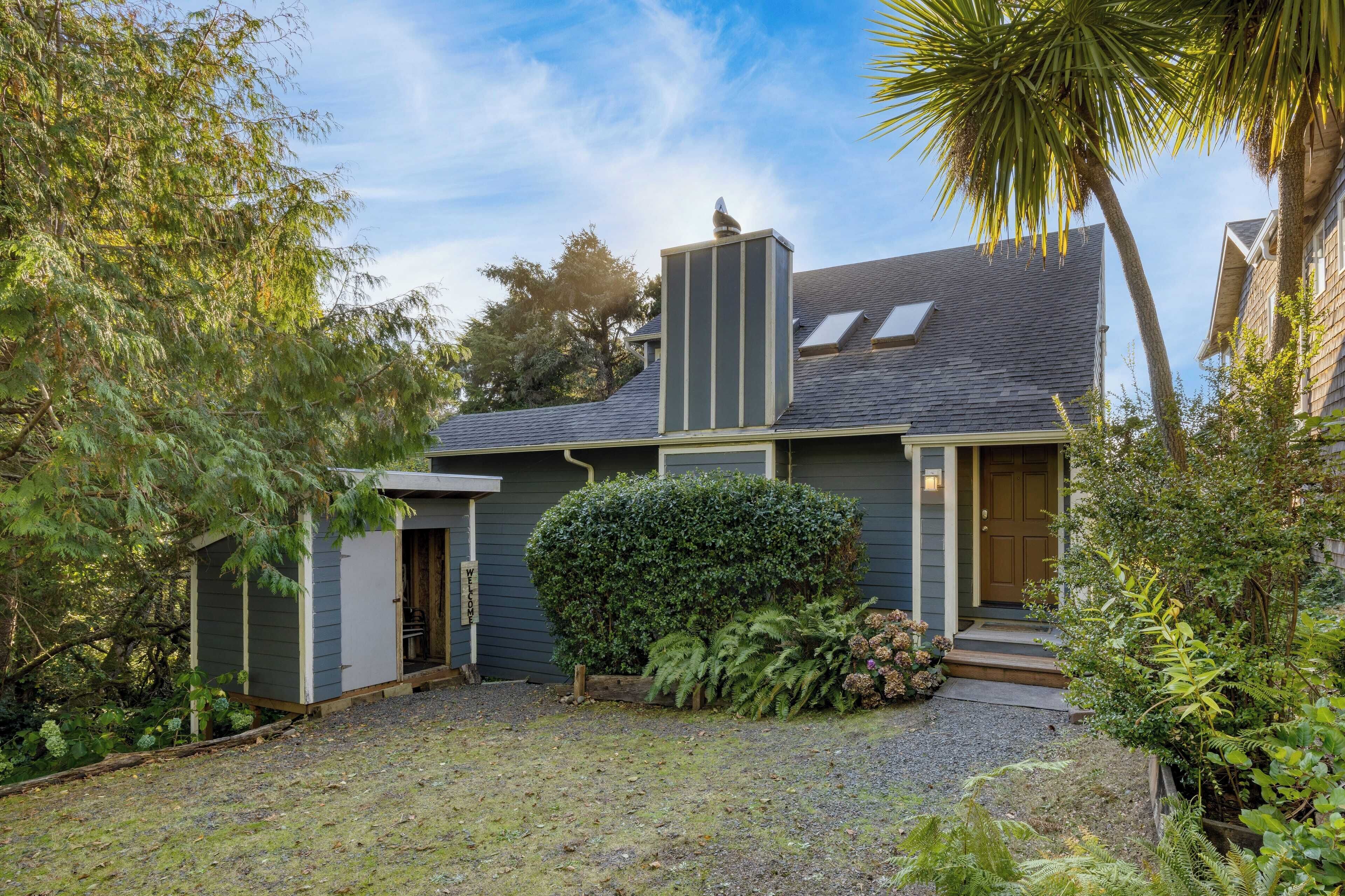 Une maison à l’extérieur gris, avec une cheminée et un petit porche.