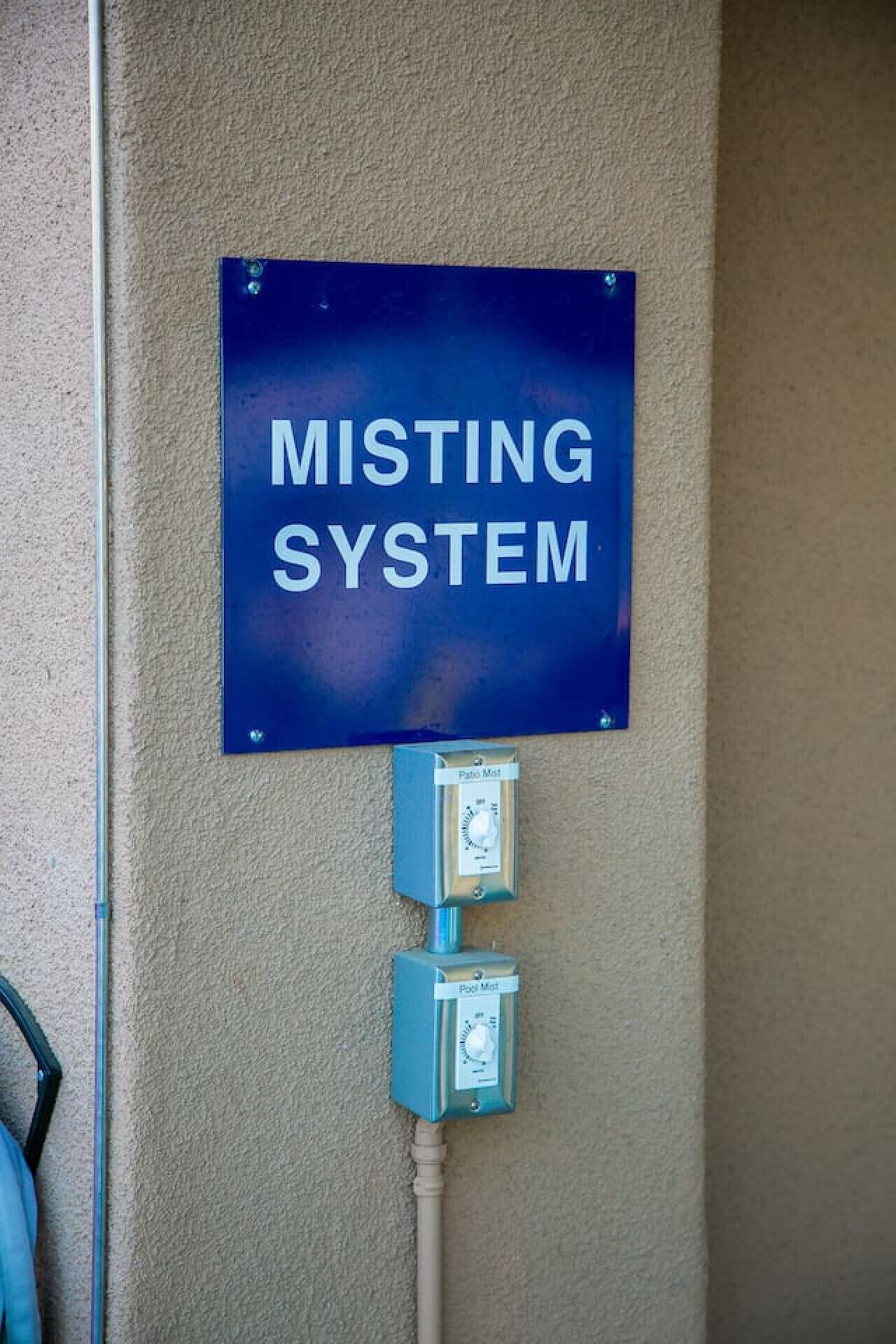 A 'MISTING SYSTEM' sign and two control boxes mounted on a wall.