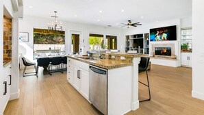 Une cuisine moderne dotée d’un îlot central, de meubles blancs et d’un lave-vaisselle encastré.