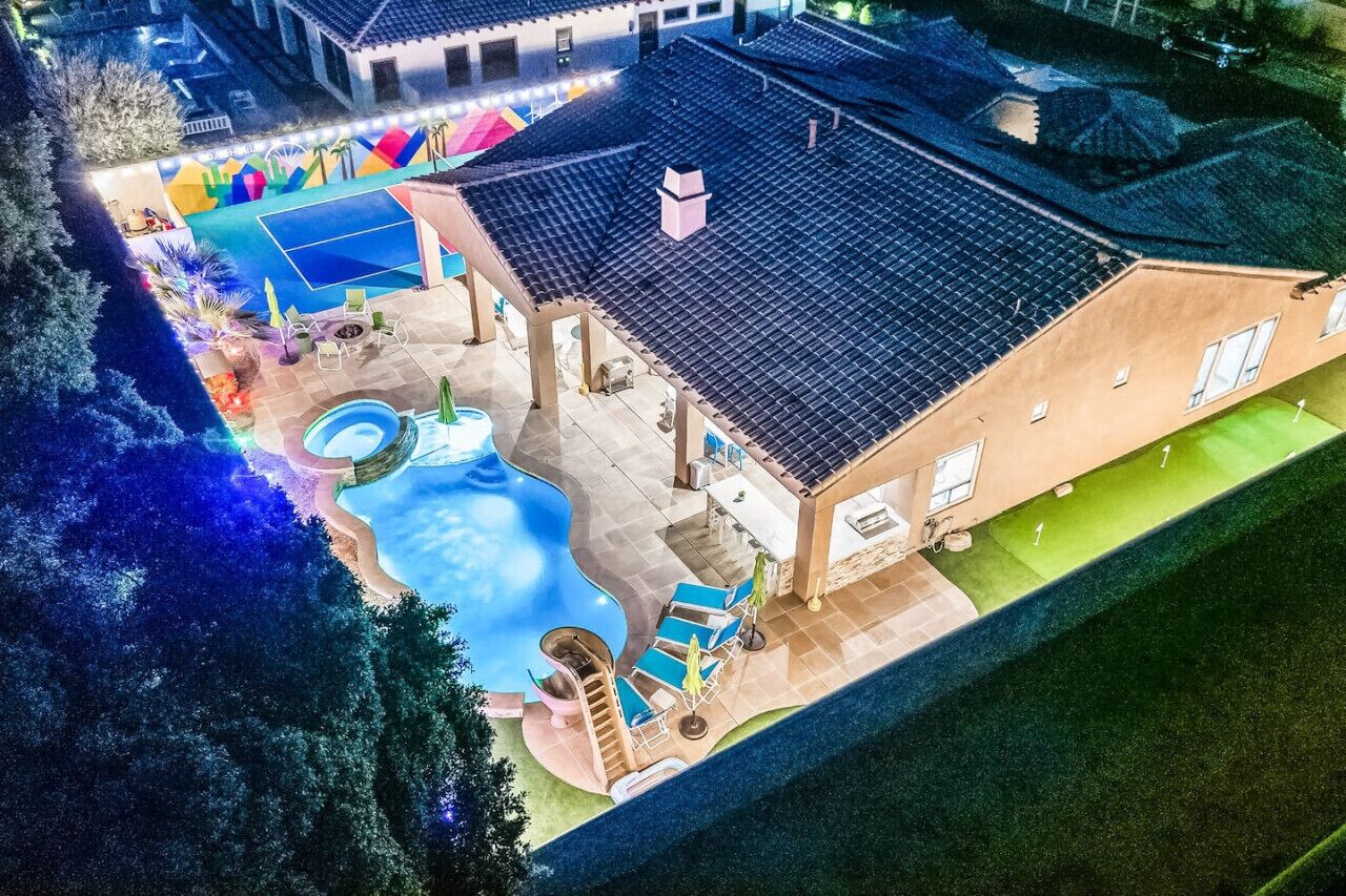 Eine Vogelperspektive eines Wohnhauses mit Schwimmbad, Sitzbereich im Freien und Tennisplatz.