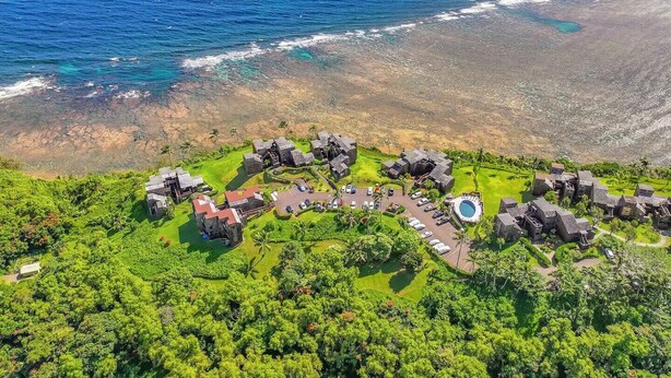 Vista aérea de un resort con varias construcciones de piedra, una piscina y abundante vegetación.