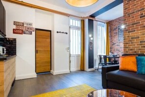 A modern living room with a black sofa, a coffee table, and a brick wall. - Appartement in the Heart of Paris Republique (Paris)