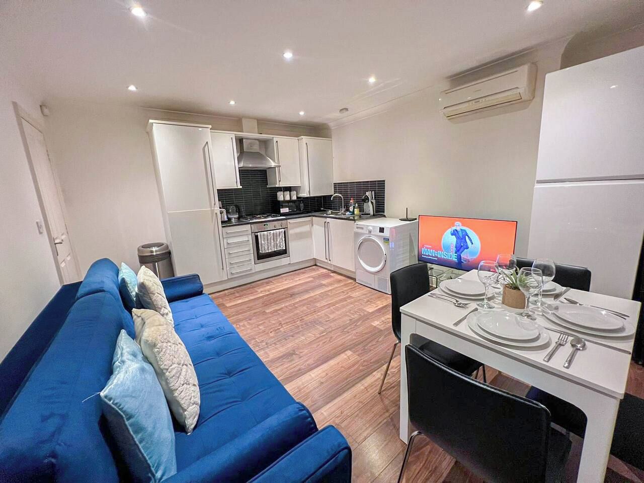 Ett kompakt bostadsutrymme med ett litet kök, en matplats och en soffa.
