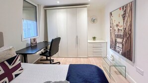 A bedroom with a bed, a desk, a chair, a wardrobe, and a painting on the wall. - 2 Bed flat w/ AC by Trafalgar square & London eye (London)