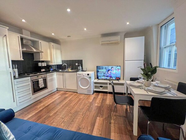 A modern kitchen with a dining area, a TV, and a washing machine.