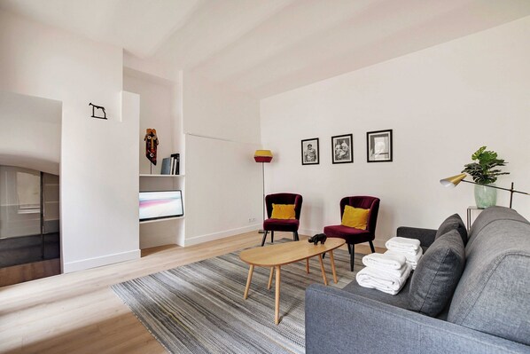 A modern living room with a sofa, two armchairs, a coffee table, and a TV. - Authentic Apartment - 2br/4p - Monnaie (Paris)