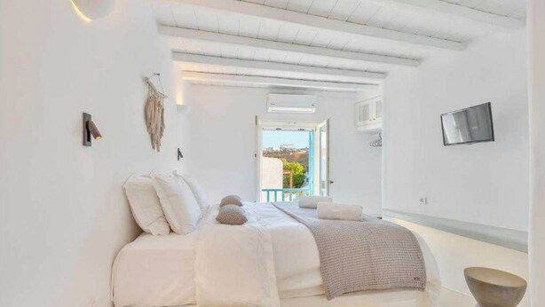 A minimalist bedroom with a bed, bedside tables, and a view of the outdoors. - Cosy Flat on the Shore - 1bd/2p - Mykonos (Mykonos)