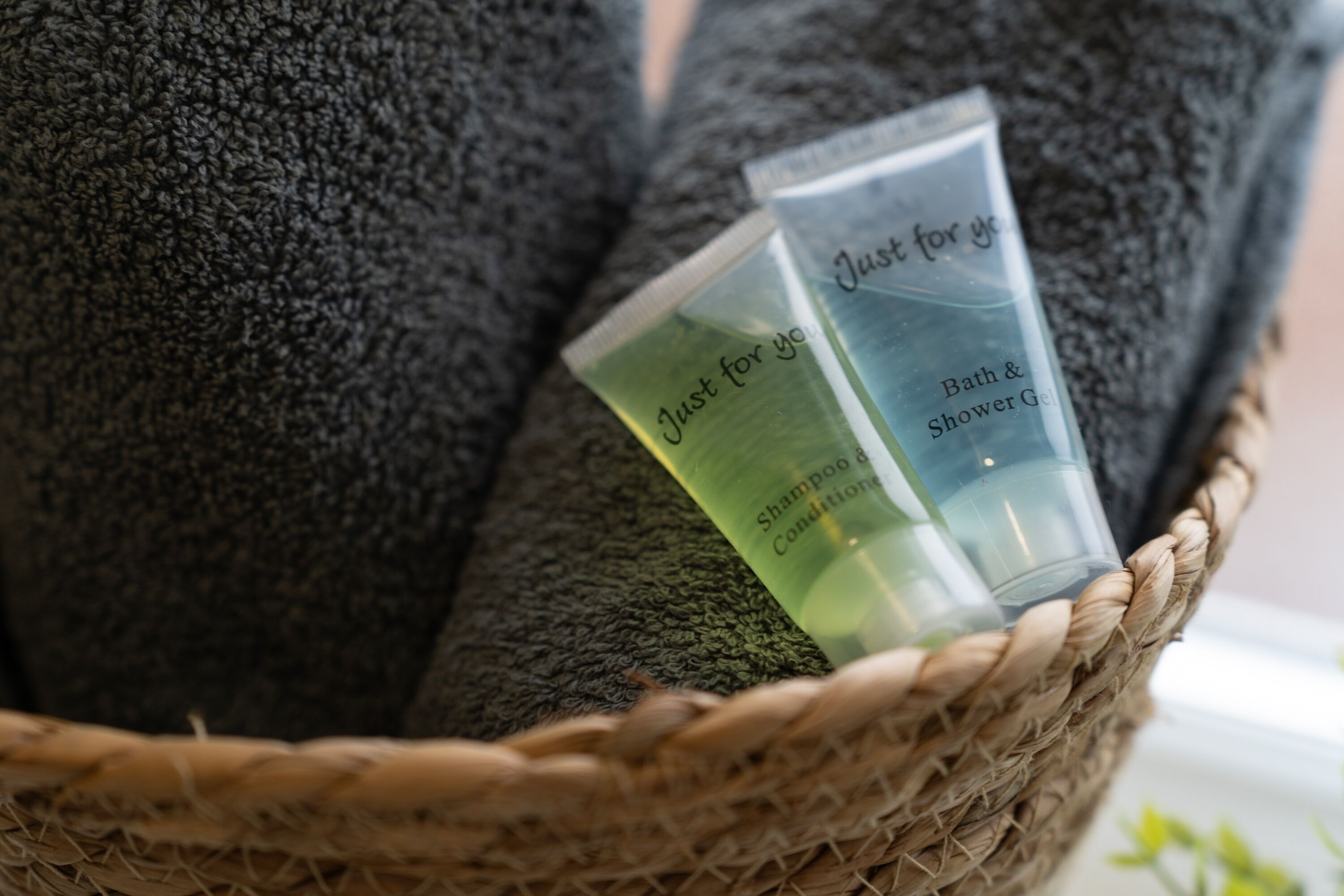 Uma cesta com um frasco de shampoo verde e um frasco transparente com etiqueta azul.