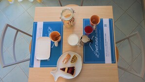 Une table dressée avec une cafetière, deux tasses, un verre de lait, une assiette de pâtisseries et un menu.