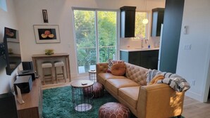 Un soggiorno moderno con un divano, poggiapiedi, un tavolino da caffè e una TV.