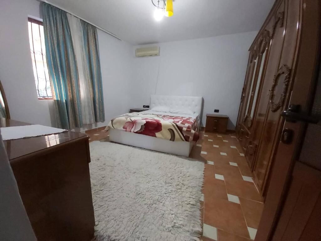 Une chambre à coucher avec un lit, un bureau, une armoire et une fenêtre avec des rideaux.