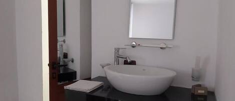 A modern bathroom with a white sink, a black countertop, and a mirror above the sink.