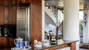 Une cuisine avec des meubles de rangement en bois, un réfrigérateur en acier inoxydable et un plan de travail orné de bols décoratifs et d’une carafe.