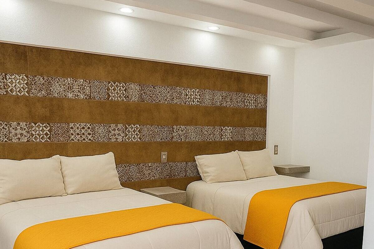 Habitación de hotel con dos camas, cabecera estampada y diseño moderno.
