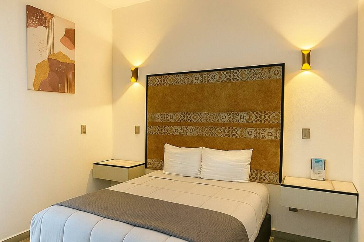 Un dormitorio moderno con una cama grande, dos mesitas de noche y una obra de arte colgada en la pared.