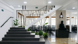 Una escalera moderna con diseño minimalista que conduce a un comedor con sillas y mesas negras.
