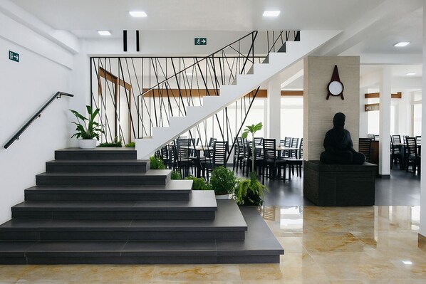 Una escalera moderna con diseño minimalista que conduce a un comedor con sillas y mesas negras.