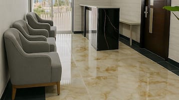Un hall d’hôtel comprenant un comptoir d’accueil, un téléviseur fixé au mur et un espace détente avec des fauteuils.
