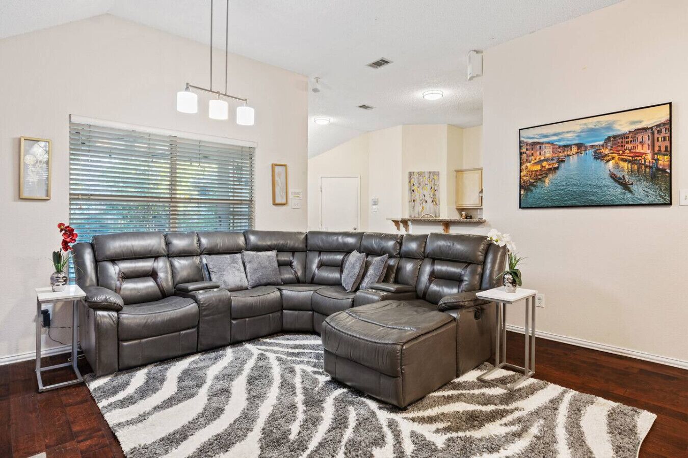 A modern living room with a sectional sofa, a patterned rug, and a cityscape painting on the wall.
