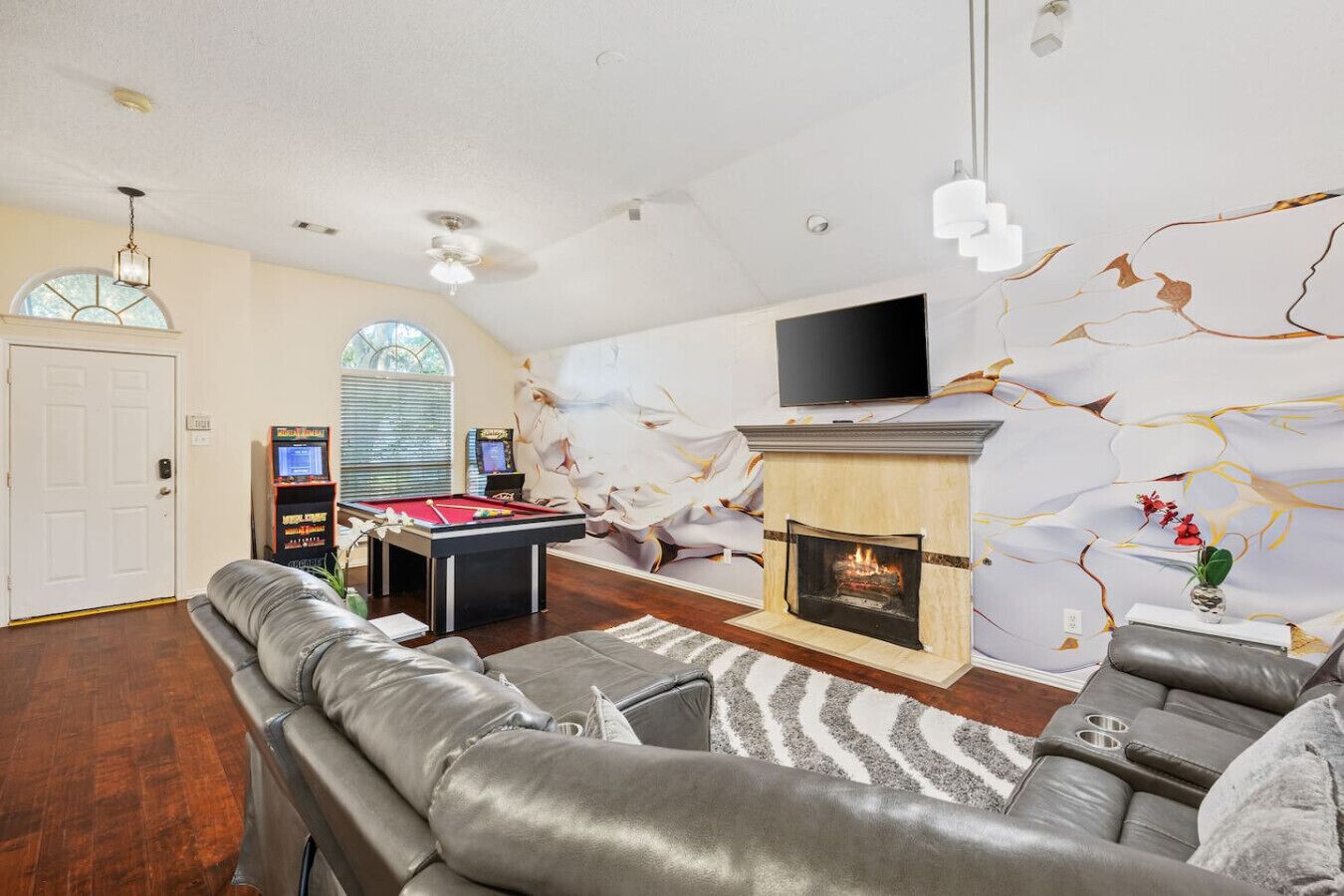 A modern living room with a fireplace, a pool table, and a flat-screen TV.
