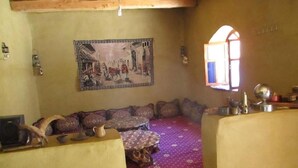 A cozy living room with a sofa set, a patterned rug, and a wall-mounted painting. - dar awlim (Imilmaiss)