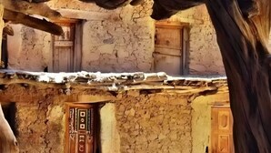A rustic building with multiple wooden doors and windows, some of which are partially open. - dar awlim (Imilmaiss)