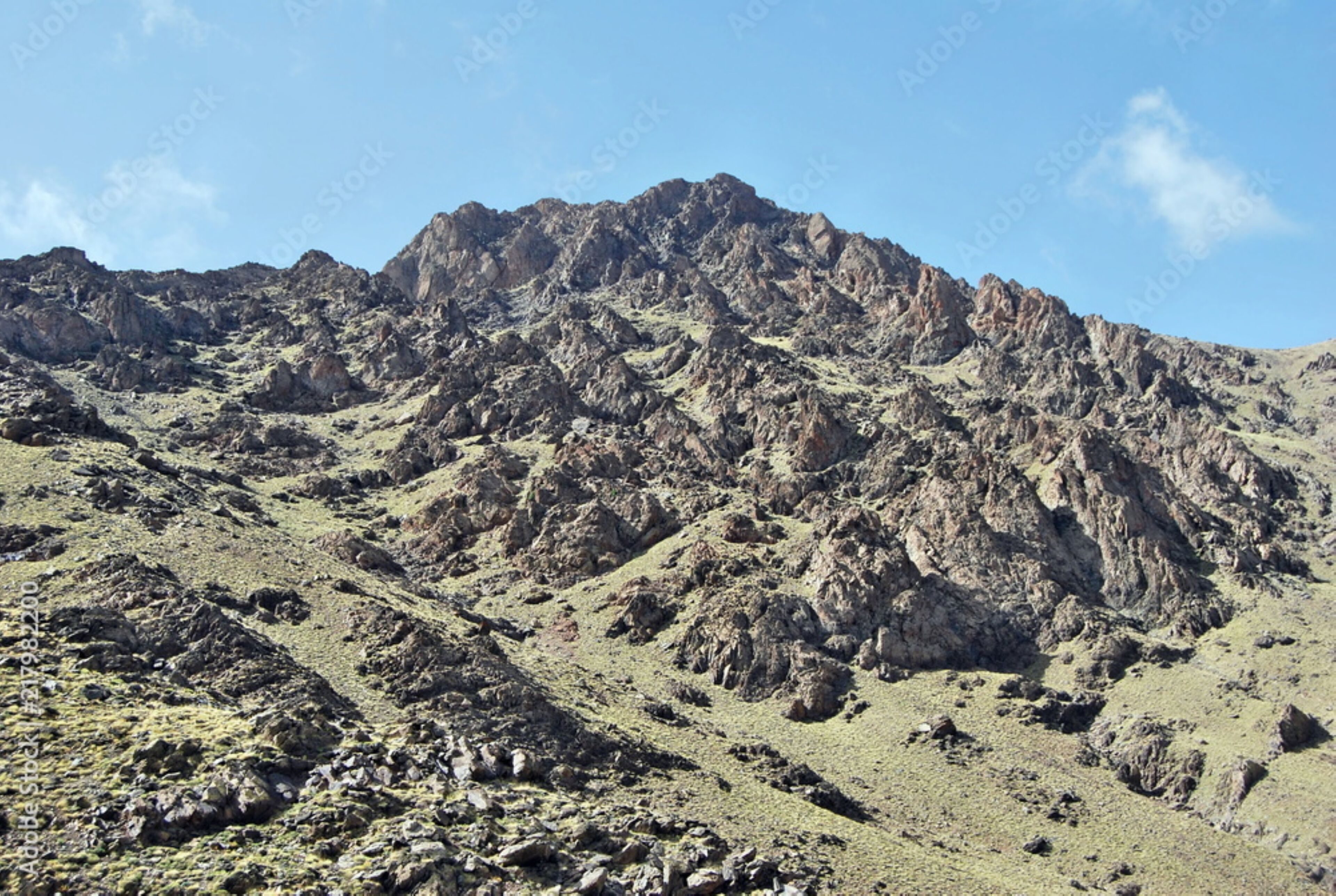 A rugged mountain landscape with rocky terrain and sparse vegetation.