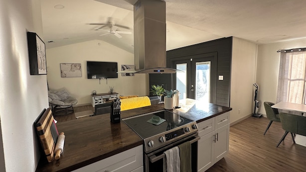 A modern kitchen with a central island, a built-in oven, and a dining area with a table and chairs. - Luxury Lane: Pet & Family Haven Near ASU & GF Base - Stock Show 7 mi - No Stairs (San Angelo)
