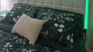 A bedroom with a bed featuring a green LED light strip, a tufted headboard, and floral-patterned bedding. - Luxury Lane: Pet & Family Haven Near ASU & GF Base - Stock Show 7 mi - No Stairs (San Angelo)
