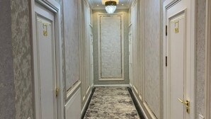 A hallway with a chandelier, white doors, and a patterned carpet. - Annur Boutique Hotel (Samarkand)