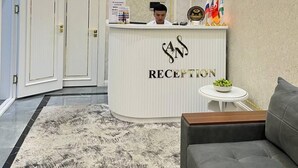 A reception area with a chandelier, a television, a reception desk, and a sofa. - Annur Boutique Hotel (Samarkand)