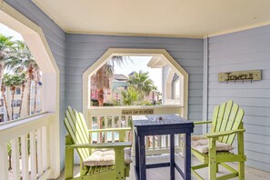 Une véranda avec deux fauteuils Adirondack verts, une petite table et un panneau indiquant : « Salty Air Retreat ».