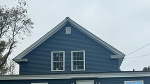 A two-story house with a front door, a small porch, and a number '26' sign. - Northern Maine Getaway-Direct Trail Access (Fort Fairfield)
