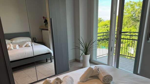 A hotel room with a bed, a potted plant, and a view of greenery outside.