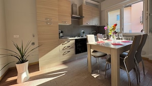 A modern kitchen with wooden cabinets, a dining table with chairs, and a potted plant.