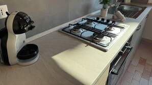 A modern kitchen with a gas stove, a coffee maker, and a sink.